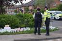 Police officers look at flowers laid at the scene of the incident in Hainault (Yui Mok/PA)