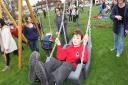 A young disabled boy enjoys a specially designed swing in the new play area
