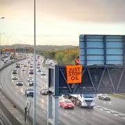 A Just Stop Oil activist on an overhead gantry on the M25.