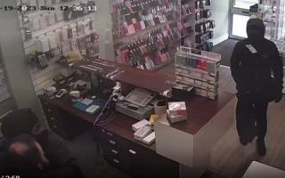 A video shows the shop owner being grabbed, whilst phones are stolen from his shop.